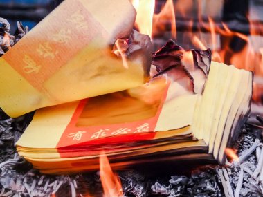 Burning Chinese joss paper or ghost money at a temple during Chi clipart