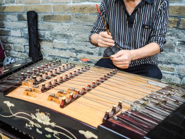 Yaşlı adam fiv ile modern bir yangqin üzerinde bambu çekiç ile oynuyor