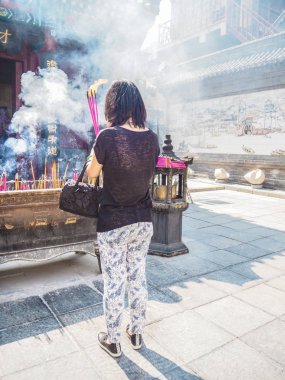 Elinde büyük yanan tütsü çubukları tutan genç bir kadın.