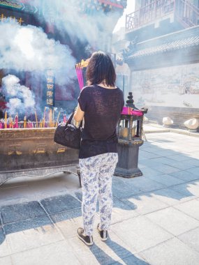 Elinde büyük yanan tütsü çubukları tutan genç bir kadın.