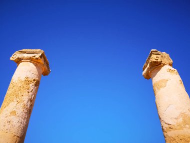 Berrak mavi güneşli gökyüzüne karşı taş antik Yunan sütunları