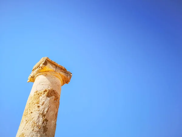 Древнегреческий столп в камне против голубого солнечного неба — стоковое фото