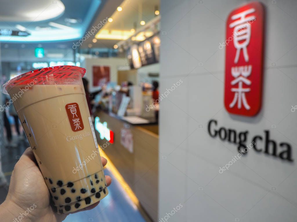 March 2019 - South Korea: Caucasian female hand holding a jumbo size black milk tea with pearls or bubble tea from the Taiwanese brand Gong Cha