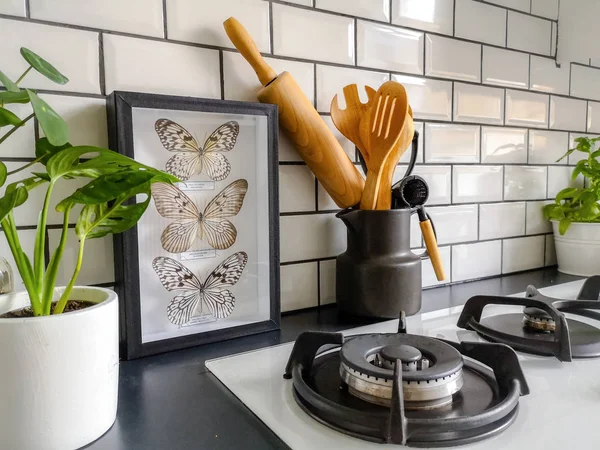 Taxidermie encadrée papillons art dans une cuisine carrelée de métro noir et blanc avec de nombreuses plantes — Photo