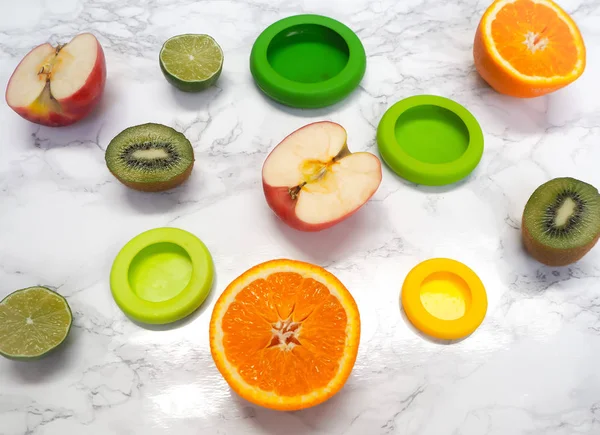 Variety of cut fruits and colorful reusable silicone food wraps for reducing food waste in a zero waste lifestyle