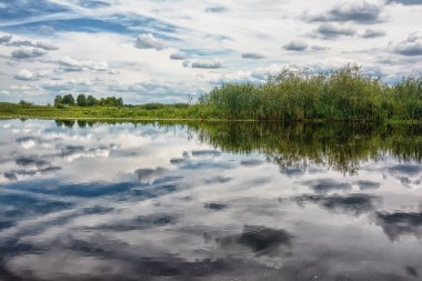Üstündeki bulutlar ile nehir banka, mavi gökyüzü güneşli gün.