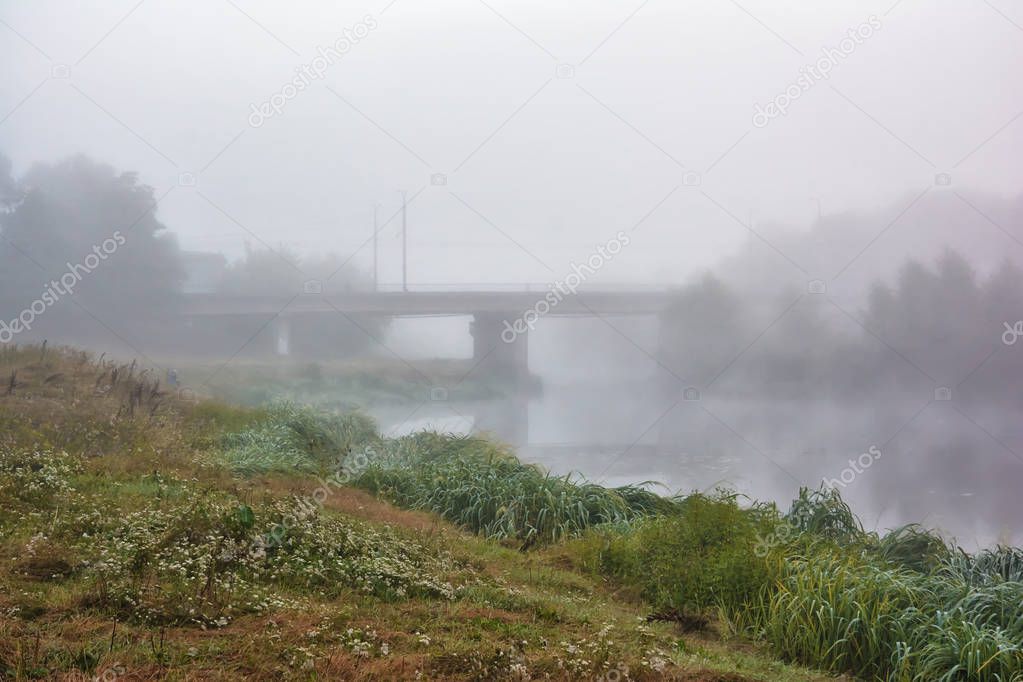 Morning fog over the river and the bridge through it.