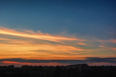Alacakaranlık, gökyüzü bulutlu şehir evlerin çatıları üzerinden.