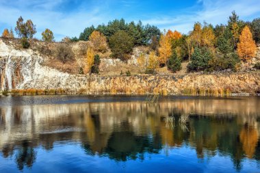 Sonbahar manzara - kayalık nerede ağaçların yaprakları sararmış bazalt gölün kıyısında.