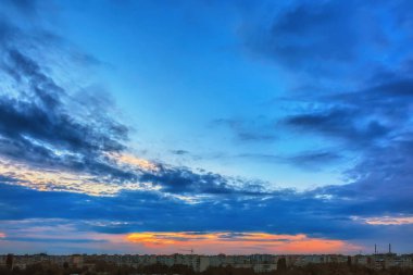 Gökyüzü bulutlu gün batımında akşam şehir üzerinde.