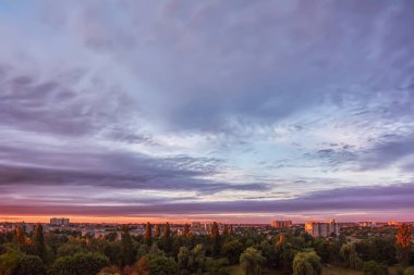 Gökyüzü bulutlu şehir binaları ve günbatımı park.