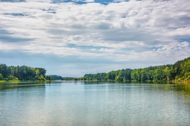 Üstündeki bulutlar ile nehir banka, mavi gökyüzü güneşli gün.