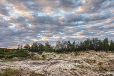Eski kum ocağı orman, toprak erozyonu, gökyüzü bulutlu gün batımında kenarına.