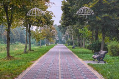 Lutsk (Ukrayna) parkında şemsiye şeklinde fener sokakları. Çok renkli kaldırımlar ve dekoratif banklar..