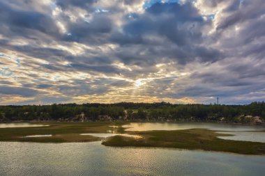 Üzerinde nehir kıyısında günbatımı, fırtına bulutları.