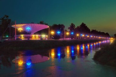 Akşam parkında şemsiye şeklinde fenerlerle aydınlatılan sokak su kanalına yansıyor. (Lutsk, Ukrayna).