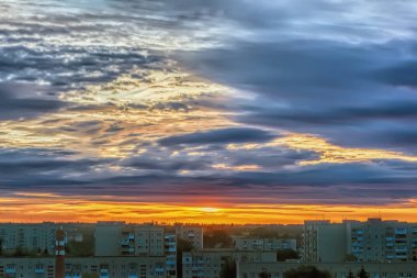 Gökyüzü bulutlu gün batımında şehir üzerinde.