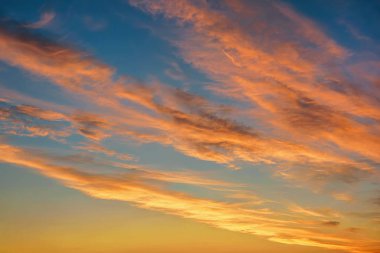 Gün batımında kırmızı ve sarı renkli bulutlarla mavi gökyüzü.