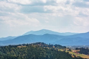 Dağlar, ormanlar ve bulutlu gökyüzü.