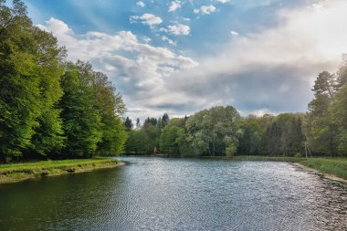 Akşam manzarası - gün batımı göl üzerinde bulutlar ve ormanlı kıyılar.