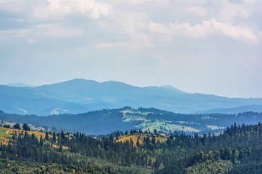 Dağlar, ormanlar ve bulutlu gökyüzü.