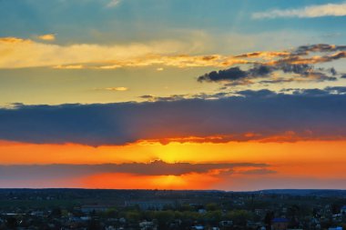 Şehrin üzerinde gün batımı, bulutlu gökyüzü..