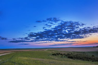Akşam kırsal manzara - mavi gökyüzü günbatımı meadows, orman ve sürülmüş alanlar üzerinde bulutlara ile.