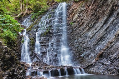 Ormanın ortasında yükseklikten dağ şelale - su düşüyor.
