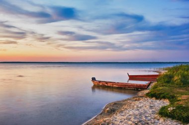 Gün batımı göl üzerinde ters banka ve iki balıkçı tekneleri sahilde silueti olduğunu.