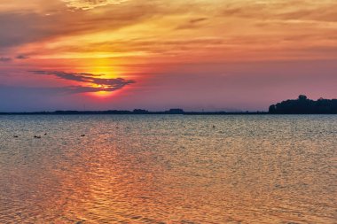 Göl günbatımı. Gökyüzü bulutlu suya yansıyan.