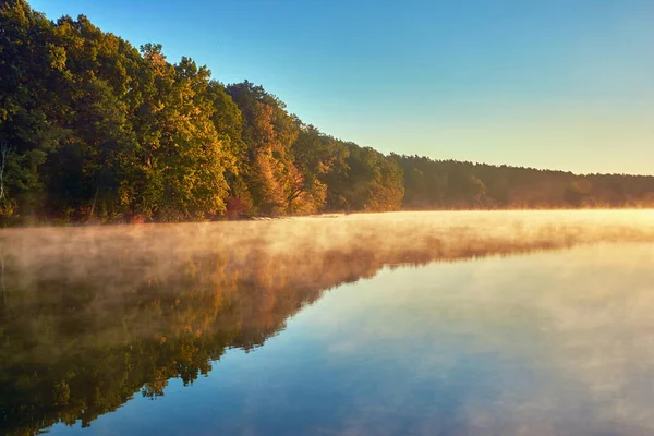 Sunrise over lake with fog over water.