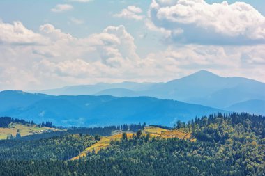 Dağlar, ormanlar ve bulutlu gökyüzü.
