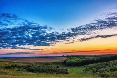 Akşam kırsal manzara - mavi gökyüzü günbatımı meadows, orman ve sürülmüş alanlar üzerinde bulutlara ile.