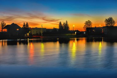 Gölet üzerinde akşam. Ağaçlı plaj fenerleri.