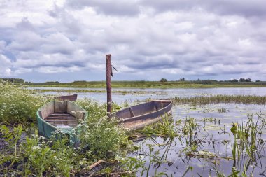 Nehir kıyısında fırtına bulutları ve ahşap botlar..