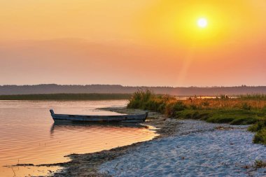 Balıkçı teknesi sahilde gündoğumu göl kenarında.