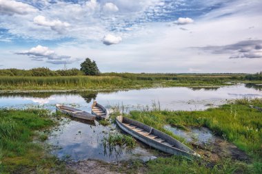 Gün batımında nehir kıyısında üç tekne.