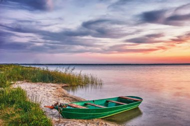 Gölde gün batımı, kıyıda balıkçı teknesi.