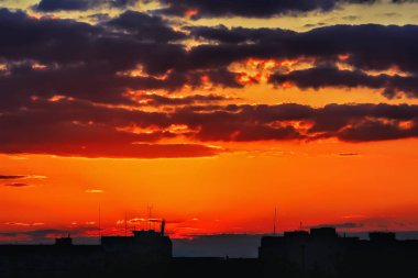 Şehir evlerinin siluetleri gökyüzü arka planında ve bulutlar gün batımında.
