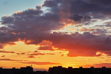 Şehir evlerinin siluetleri gökyüzü arka planında ve bulutlar gün batımında.