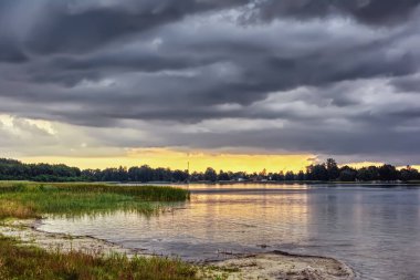 Gün batımında gölün kıyısında fırtına.