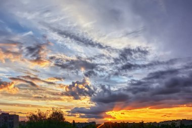 Şehir evlerinin siluetleri gökyüzü arka planında ve bulutlar gün batımında.