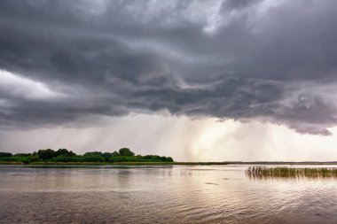 Göl üzerinde fırtına ve gün batımında kıyı şeridi.