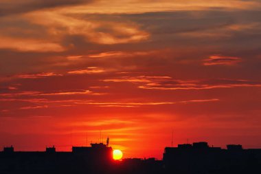 Şehir evlerinin siluetleri gökyüzü arka planında ve bulutlar gün batımında.