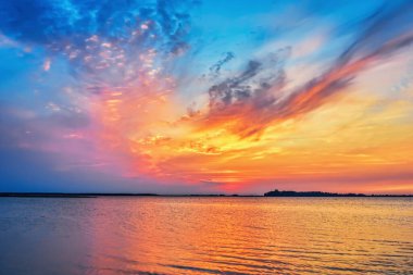 Gölün üzerinde güzel bir gün batımı, bulutlar suya yansıyan gökyüzü..