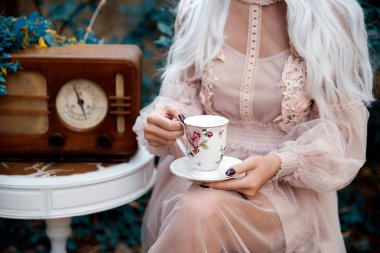 Çiçek desenli çay bardağı tutan kadının yakın çekim