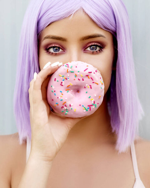 Портрет красивой молодой женщины, позирующей с пончиком
