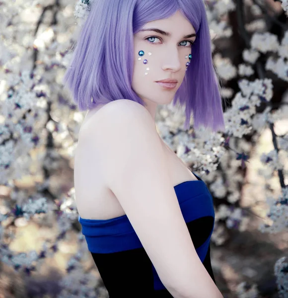 Young woman with purple hair standing near blossom tree