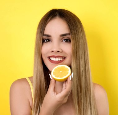 Limon dilimiyle poz veren genç bir kadın.
