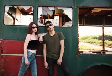 Terk edilmiş arabanın yanında duran genç çift.